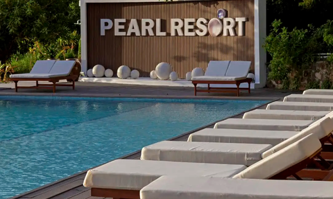 Ein einladender Poolbereich im Pearl Resort, umgeben von Liegen und einer stilvollen Wand mit dem Resort-Namen.