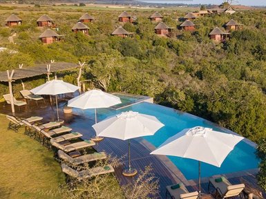 Ein atemberaubender Blick auf eine Lodge mit einem Pool, umgeben von üppiger Natur und gemütlichen Liegen unter Sonnenschirmen.