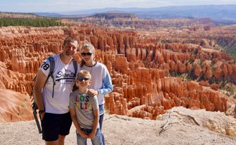 Eine Familie steht am Rand des Bryce Canyon, umgeben von beeindruckenden roten Felsformationen und einer weiten Landschaft.