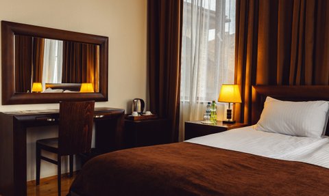 Ein gemütliches Hotelzimmer mit einem großen Bett, einem Schreibtisch und warmem Licht von einer Tischlampe.