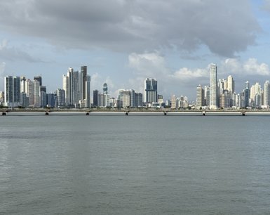 Die Skyline von Panama City zeigt beeindruckende Wolkenkratzer, reflektierend im stillen Wasser des Meeres.