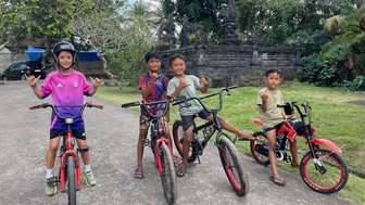 Kinder fahren gemeinsam mit einheimischen Balinesen auf dem Land Fahrräder – Bali mit Kindern