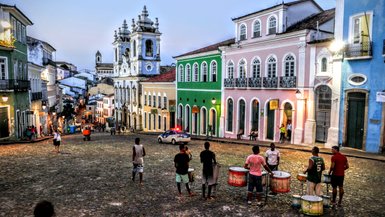 Die steilen Straßen von Salvador sind mit historischen Gebäuden gesäumt, während Musiker mit Trommeln die Atmosphäre beleben.
