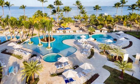 Ein atemberaubender Blick auf einen Poolbereich mit Palmen und Liegen, der sich direkt am Meer erstreckt.