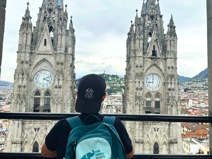 Ein junger Mann mit einem schwarzen Hut blickt auf die beeindruckenden Türme einer Kathedrale in der Stadt.
