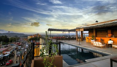 Der Blick von der Dachterrasse zeigt einen Pool und eine entspannte Atmosphäre mit Blick auf die Stadt und den Himmel.