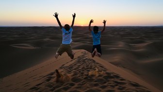 Kinder genießen den Sonnenuntergang in den Sanddünen der Sahara – Familienreise nach Marokko