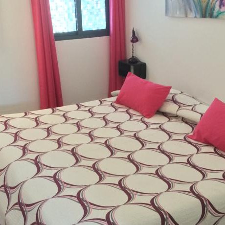 Ein gemütliches Schlafzimmer mit einem großen Bett, das mit einem kreisförmigen Muster und pinken Kissen dekoriert ist.