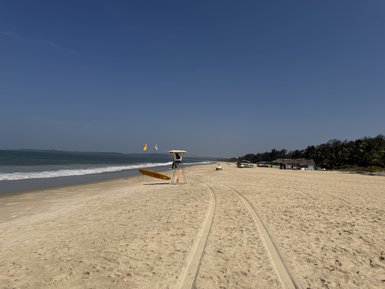 Ein weitläufiger Strand mit sanften Wellen, einem Rettungsboot und einem klaren blauen Himmel, der Ruhe ausstrahlt.