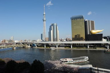 Der Blick auf die Tokyo Skytree, die majestätisch über die Stadt ragt, während ein Boot auf dem Fluss fährt.