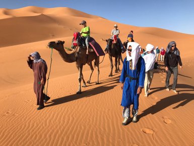 Menschen führen Kamele durch die Sanddünen – Marokko Familienreise