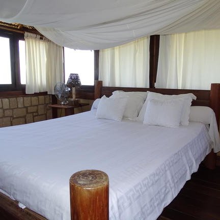 Ein helles, einladendes Schlafzimmer mit einem großen Bett, umgeben von Fenstern und sanften Vorhängen.