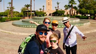 Familie und Reiseleiter stehen gemeinsam vor der historischen Koutoubia-Moschee in Marrakesch – Marokko mit Kindern