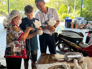 Kräutersverpacken von einheimischer Frau und Kind – Thailand Familienreise