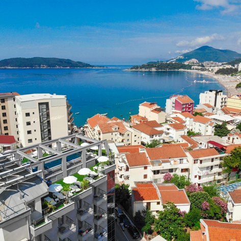 Ein atemberaubender Blick auf die Küste von Budva, mit bunten Gebäuden und dem glitzernden blauen Wasser im Hintergrund.