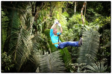 Abenteuerlicher Zipline-Flug eines Mannes über das grüne Blätterdach im tropischen Wald – Mexiko mit Kindern