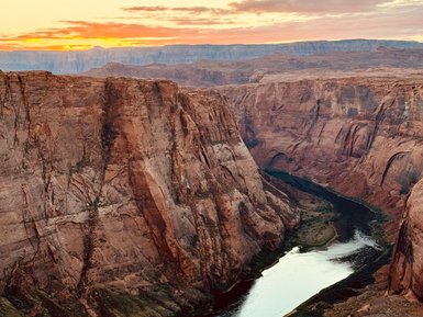 Die beeindruckende Schlucht von Horseshoe Bend wird von einem ruhigen Fluss umschlungen, während die Sonne untergeht.