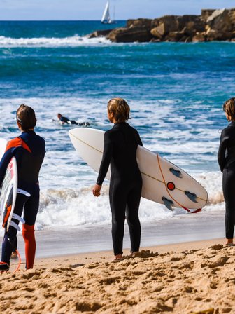 Drei Kinder warten auf die nächste Welle zum surfen