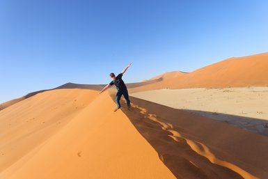 Ein Junge steht auf dem Kamm einer Sanddüne in der Wüste - Namibia Urlaub mit Kindern