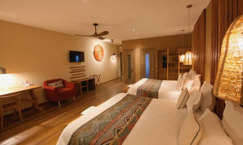 Ein modernes Hotelzimmer mit zwei Betten, warmen Holztönen und stilvollen Lampen, die eine gemütliche Atmosphäre schaffen.