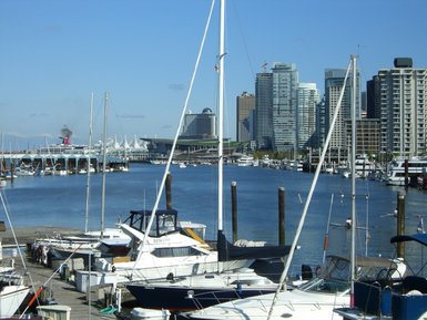 Ein Blick auf den Hafen von Vancouver mit vielen Booten und modernen Wolkenkratzern im Hintergrund unter klarem Himmel.