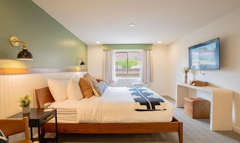 Geräumiges Zimmer mit einem großen Bett, umgeben von warmen Farben und modernen Lichtern, ideal für entspannende Übernachtungen.