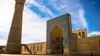 Die beeindruckende Mir-i-Arab-Madrasa in Buchara, mit ihrem hohen Minarett und kunstvollen Mosaiken, strahlt historische Pracht aus.