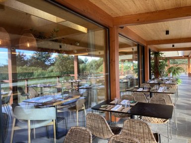 Ein elegantes Restaurant mit Holzelementen, das eine einladende Atmosphäre und Blick auf die grüne Umgebung bietet.
