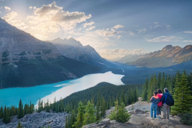 Ein Paar und ein Kind stehen auf einem Aussichtspunkt und bewundern die atemberaubende Landschaft des Icefield Parkway.