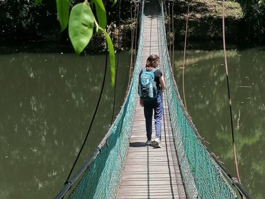 Frau geht über eine Hängebrücke, die einen See im Sepilok Rainforest Discovery Centre überspannt – Malaysia & Borneo Reise mit Kindern