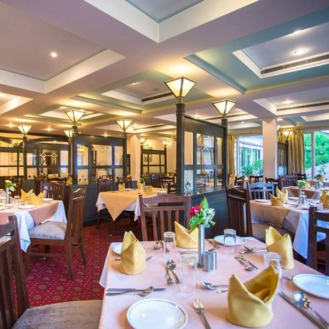 Ein elegantes Restaurant mit Holzmöbeln, schön gedeckten Tischen und warmem Licht, das eine einladende Atmosphäre schafft.