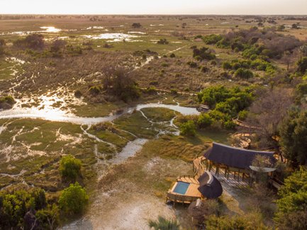 Eine weitläufige Landschaft im Okavango mit üppigem Grün und Wasserläufen, die durch das Gelände fließen.