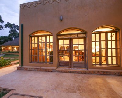 Die Fassade des Brovad Sands Lodge zeigt große Fenster, die warmes Licht in den Abend bringen und eine einladende Atmosphäre schaffen.
