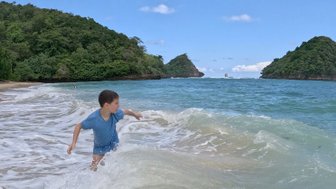 Kind spielt am Strand von Gatra Beach – Bali Familienreise