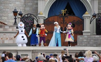 Eine Gruppe von Disney-Charakteren, darunter Elsa und Mickey Mouse, steht auf einer Bühne im Magic Kingdom.