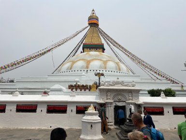 Der Bodhnath Stupa in Nepal, umgeben von bunten Gebetsfahnen, zieht zahlreiche Besucher an, die die heilige Stätte erkunden.