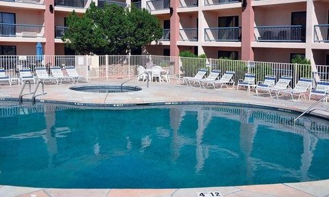 Ein einladender Poolbereich mit klarem Wasser, umgeben von Liegen und einem Whirlpool, ideal für Entspannung.