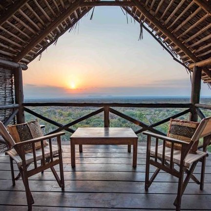 Eine gemütliche Terrasse mit zwei Stühlen und einem Tisch bietet einen atemberaubenden Blick auf den Sonnenuntergang über der Landschaft.