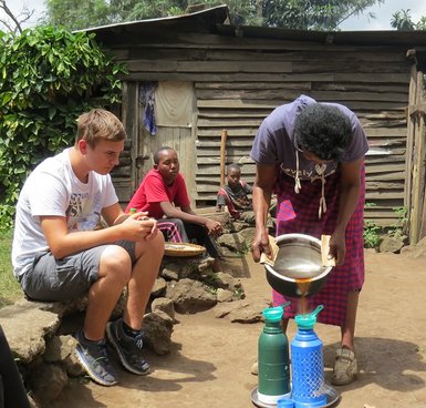 Frau röstet und kocht traditionellen Kaffee im Dorfalltag – Tansania mit Kindern