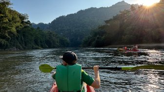 Junge paddelt in Kanu auf ruhigen Fluss in Kanchanaburi - Thailand mit Kindern