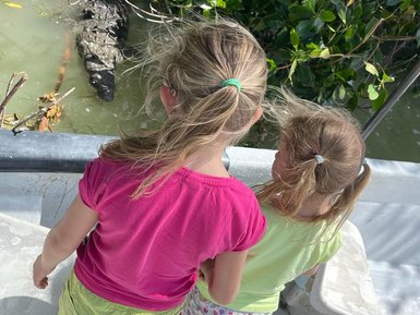 Kinder an Bord eines Bootes schauen auf ein Krokodil im Wasser des Rio Lagartos Naturreservats – Mexiko mit Kindern