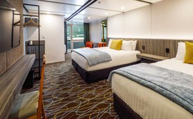 Zwei komfortable Betten mit hellen Kissen und einer warmen Decke in einem modernen Hotelzimmer.