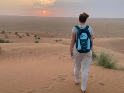Frau läuft in der Wahiba-Wüste beim Sonnenuntergang – Oman Reise mit Kindern