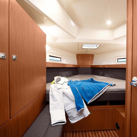 Ein gemütlicher Innenraum einer Yacht mit einem großen Bett und einem Fenster, das Tageslicht hereinlässt.