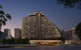 Ein modernes Hotelgebäude mit geschwungener Architektur, beleuchtet in der Dämmerung, umgeben von städtischen Hochhäusern.
