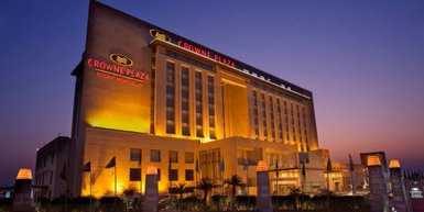 Das Crowne Plaza Hotel in Neu-Delhi erstrahlt in warmem Licht, während der Abendhimmel in sanften Farben leuchtet.