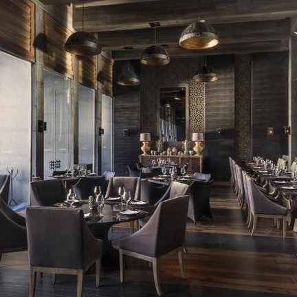 Ein elegantes Restaurant mit dunklem Holzinterieur, stilvollen Stühlen und einem einladenden Ambiente für Gäste.
