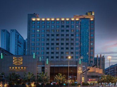 Das Tianfu Sunshine Hotel erstrahlt in der Dämmerung, umgeben von modernen Gebäuden und beleuchteten Straßenlaternen.