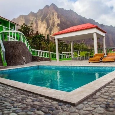 Ein einladender Pool in einer grünen Pousada, umgeben von beeindruckenden Bergen und einem klaren Himmel.