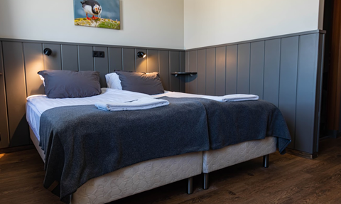 Ein gemütliches Hotelzimmer mit zwei Betten, grauen Decken und einem modernen, minimalistischen Design.